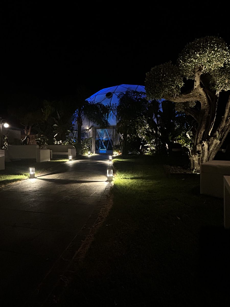 Vialetto illuminato del giardino verso la cupola geodetica di sera