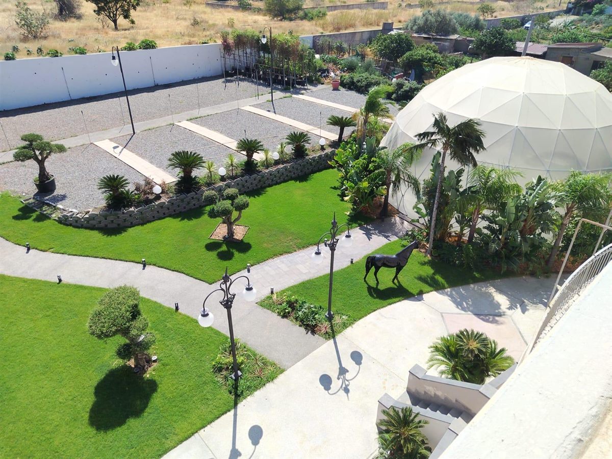 Vista aerea diurna del giardino di Villa CaStè con cupola, palme e vialetti